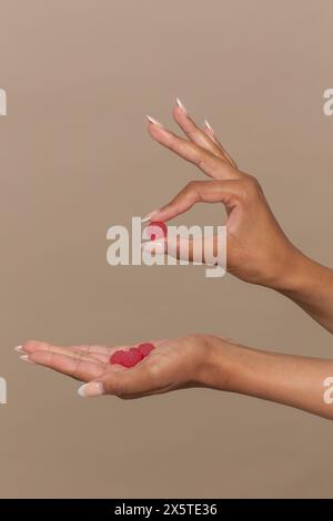 Studio-Aufnahme von Frauenhänden, die frische Himbeeren halten Stockfoto