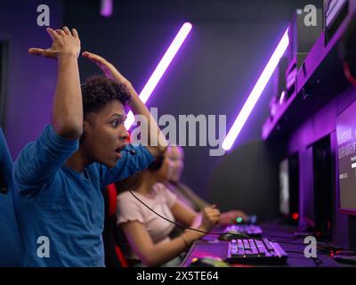 Frustrierter junger Mann, der Videospiele mit Freunden im Spielclub spielt Stockfoto