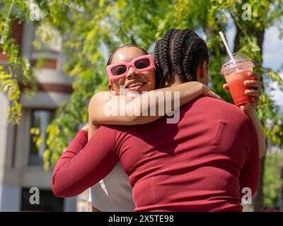 Zwei Freundinnen, die sich an sonnigem Tag umarmen Stockfoto