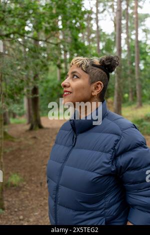 Lächelnde reife Frau, die im Wald wandert Stockfoto