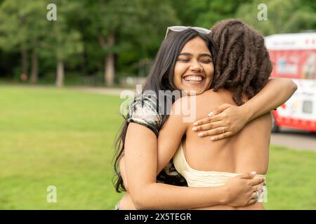 Porträt von Freunden, die sich im Park umarmen Stockfoto