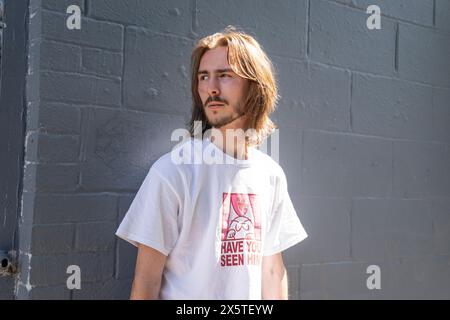 Junger Mann, der draußen im Sonnenlicht steht Stockfoto