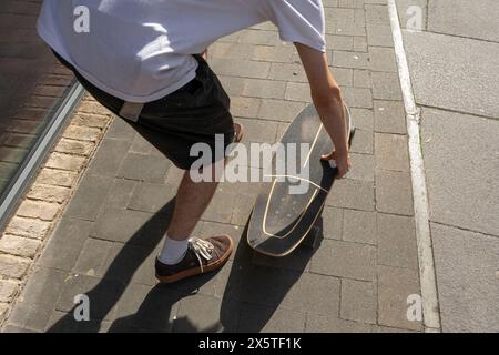 Junger Mann Skateboarden auf Bürgersteig Stockfoto