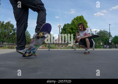 Ein Mann nimmt einen Freund auf, der Skateboard-Tricks macht Stockfoto