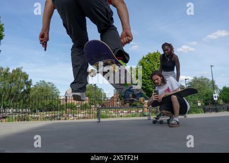 Ein Mann nimmt einen Freund auf, der Skateboard-Tricks macht Stockfoto