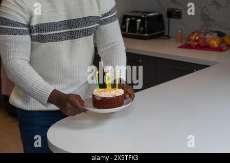 Der Mittelteil eines Mannes, der eine kleine Geburtstagskuche hält Stockfoto
