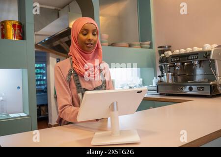 Junge Frau im Hijab, die im Café arbeitet Stockfoto