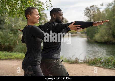 Yogalehrer, der einem Mann beim Yoga im Park hilft Stockfoto