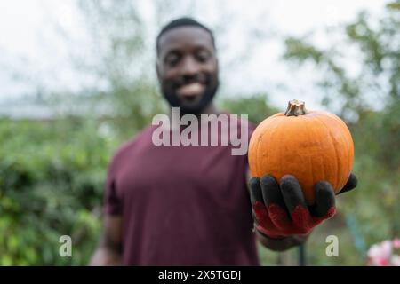 Porträt eines lächelnden Mannes, der Kürbis im städtischen Garten hält Stockfoto