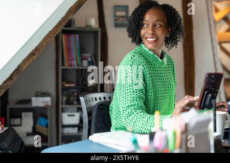 Lächelnde Geschäftsfrau mit Smartphone am Schreibtisch im Büro Stockfoto