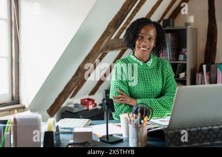 Porträt einer lächelnden Geschäftsfrau, die im Büro am Schreibtisch sitzt Stockfoto