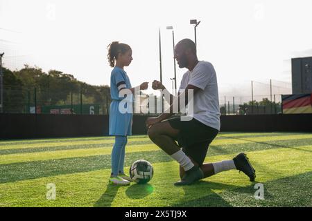 Coach und Mädchen (6-7) auf dem Fußballfeld Stockfoto