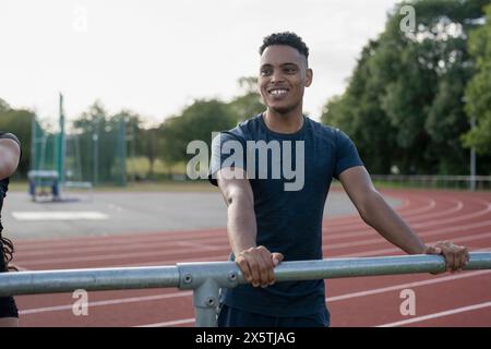 Athlet, der auf dem Geländer auf der Sportbahn ruht Stockfoto
