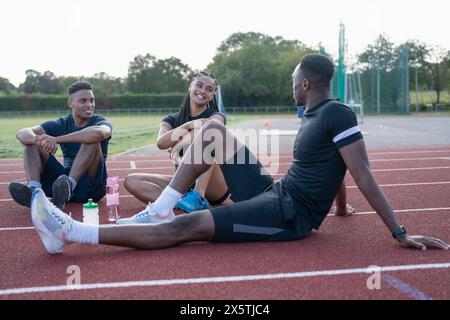 Gruppe von Athleten, die nach dem Training auf der Sportbahn ruhen Stockfoto