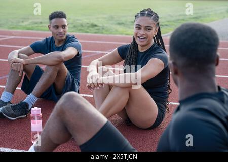 Gruppe von Athleten, die nach dem Training auf der Sportbahn ruhen Stockfoto