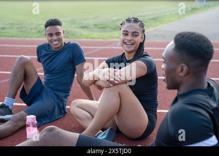 Gruppe von Athleten, die nach dem Training auf der Sportbahn ruhen Stockfoto