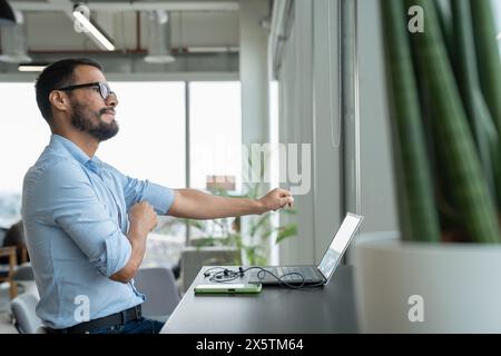 Geschäftsmann mit Laptop, der in einem modernen Büro arbeitet Stockfoto