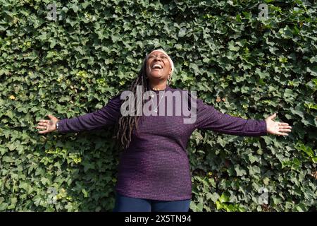 Porträt einer schönen Frau mit Dreadlocks vor der Efeuwand Stockfoto