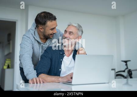 Männliches Paar, das zu Hause einen Laptop benutzt Stockfoto