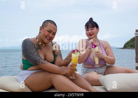 Fröhliche Frauen trinken Cocktails und entspannen sich in der Nähe der Bucht Stockfoto