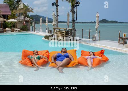 Gruppe von fröhlichen Frauen, die sich auf den Floßbooten im Swimmingpool entspannen Stockfoto