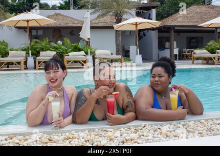 Gruppe fröhlicher Frauen, die Cocktails trinken und sich am Pool entspannen Stockfoto