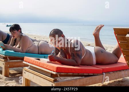 Eine Gruppe von Frauen, die sich am Strand entspannen und lesen Stockfoto