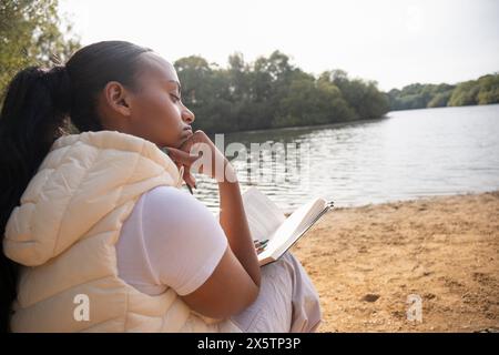 Frau liest Buch am Seeufer Stockfoto