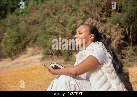 Porträt einer lächelnden Frau mit Buch am Strand Stockfoto