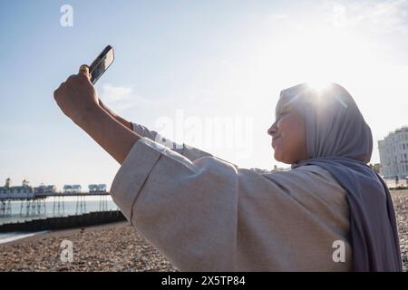 Muslimische Frau macht Selfie auf dem Meer an sonnigen Tagen Stockfoto