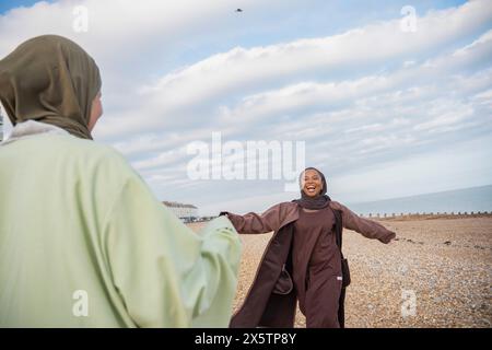 Zwei muslimische Frauen grüßen am Strand Stockfoto