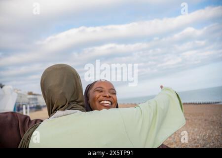 Zwei muslimische Frauen umarmen sich am Strand Stockfoto