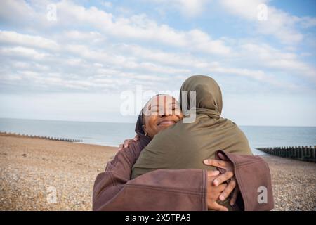 Zwei muslimische Frauen umarmen sich am Strand Stockfoto