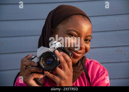 Porträt einer lächelnden muslimischen Frau, die mit einer analogen Kamera fotografiert Stockfoto