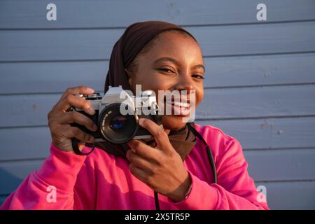 Porträt einer lächelnden muslimischen Frau, die mit einer analogen Kamera fotografiert Stockfoto