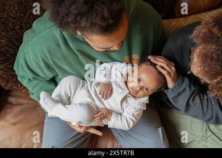 Vater hält die Tochter, Mutter berührt den Kopf des Babys Stockfoto