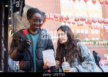 Porträt von zwei fröhlichen Frauen mit Essen zum Mitnehmen in Chinatown Stockfoto