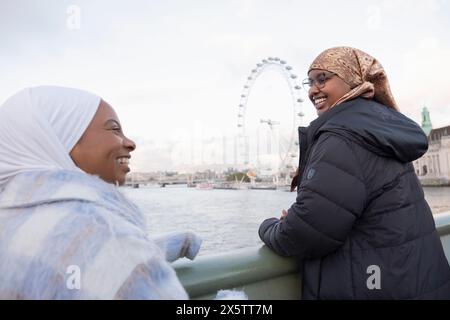 Großbritannien, London, weibliche Touristen in Hijabs mit Blick auf das London Eye über der Themse Stockfoto