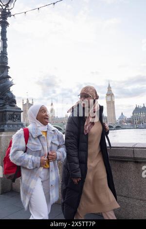 Großbritannien, London, Junge weibliche Touristen in Hijabs, die entlang der Themse spazieren Stockfoto