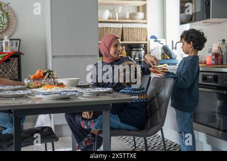 Mutter und Söhne (2-3, 6-7) essen zu Hause Stockfoto