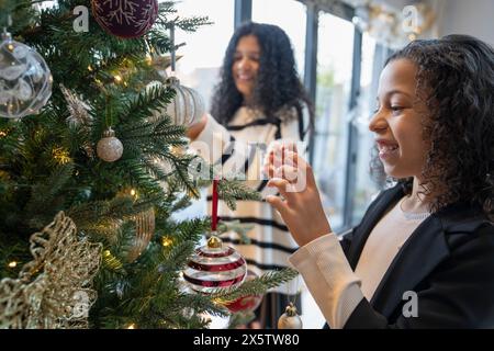 Schwestern schmücken den Weihnachtsbaum zu Hause Stockfoto