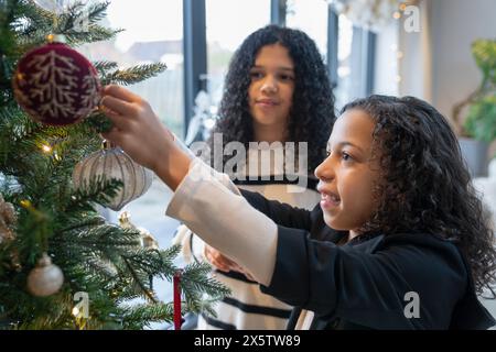 Schwestern schmücken den Weihnachtsbaum zu Hause Stockfoto