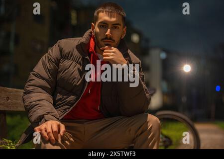 Porträt eines jungen Mannes, der nachts auf einer Bank sitzt Stockfoto