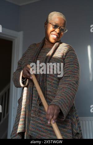 Reife Frau, die im Wohnzimmer den Boden fegt Stockfoto