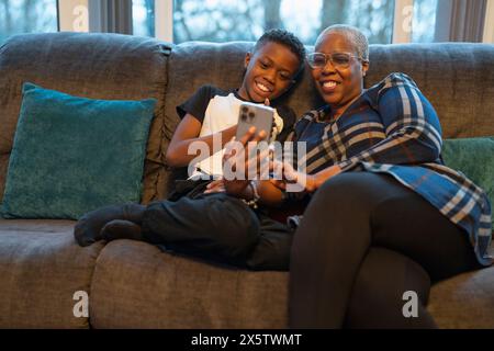 Großmutter und Enkel mit Smartphone sitzen auf Sofa Stockfoto