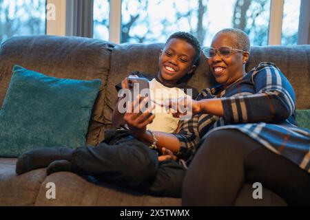 Großmutter und Enkel mit Smartphone sitzen auf Sofa Stockfoto