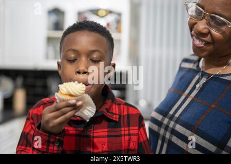 Junge mit Großmutter, der frisch gebackene Cupcakes probiert Stockfoto