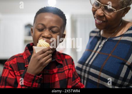 Junge mit Großmutter, der frisch gebackene Cupcakes probiert Stockfoto