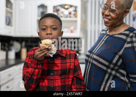 Junge mit Großmutter, der frisch gebackene Cupcakes probiert Stockfoto