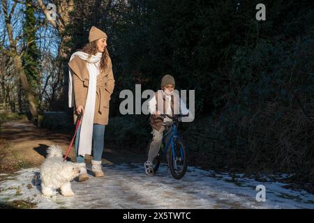 Mutter und Sohn (6-7) machen einen Spaziergang am Winternachmittag Stockfoto